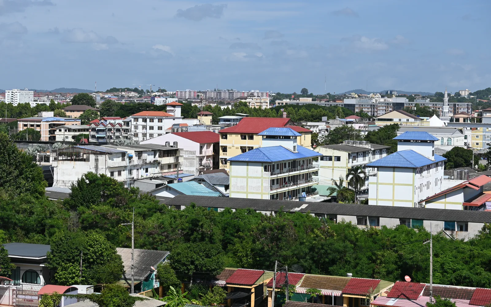 A suburban neighborhood with colorful rooftops, low-rise buildings, and mature green trees